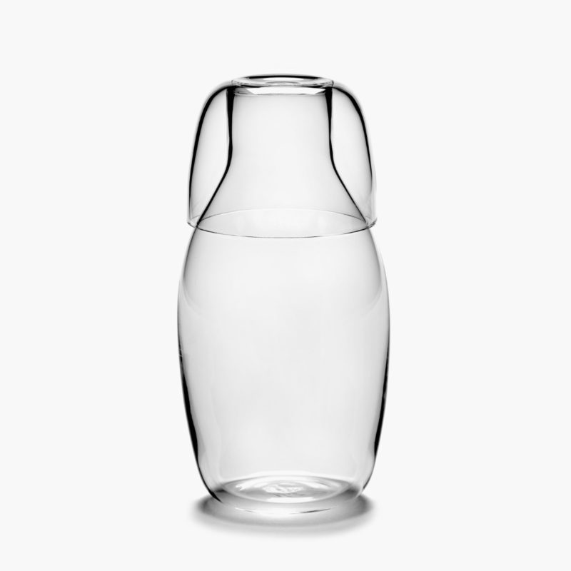 conjunto apilado de jarra y vaso bajo de 75 y 20 cl de vidrio potásico de la colección Passe-partout diseñada por Vincent Van Duysen. Sobre fondo crudo.