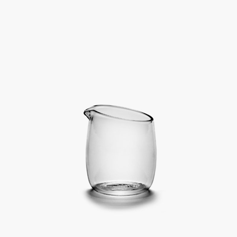 jarra para leche de 12,5 cl de vidrio de borosilicato de la colección Passe-partout diseñada por Vincent Van Duysen. Sobre fondo crudo.copa de tallo medio de 25 cl de vidrio potásico de la colección Passe-partout diseñada por Vincent Van Duysen. Sobre fondo crudo.
