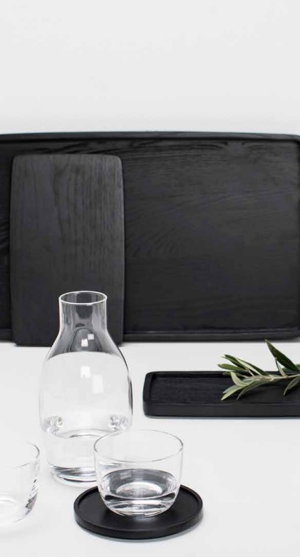 conjunto productos passre-partout, una botella y una vaso de cristal y algunas bandejas de madera oscura